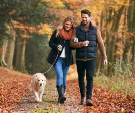 loving-couple-walking-with-pet-golden-retriever-dog-along-autumn-woodland-path-through-trees-2